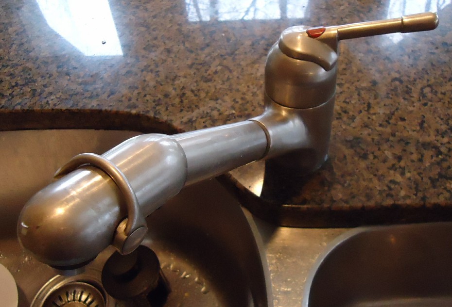 Newly installed chrome kitchen faucet at a stainless steel sink