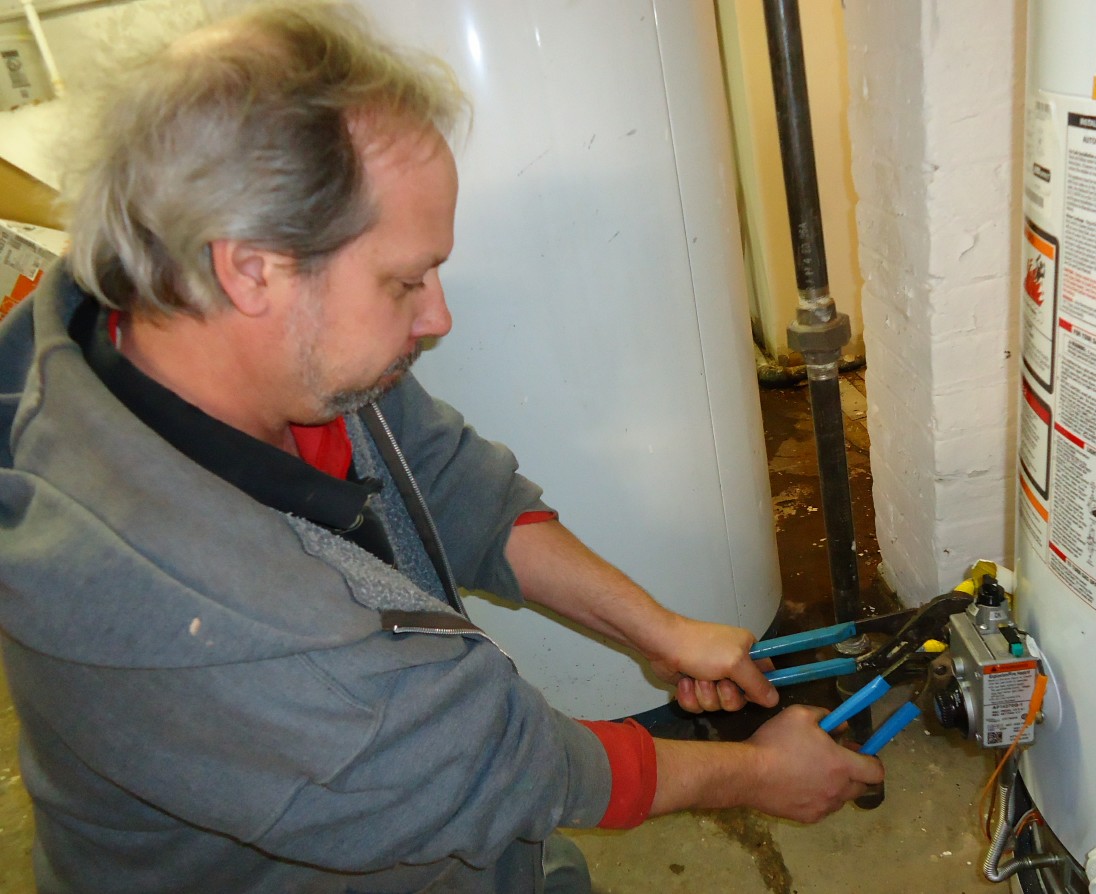 Plumber tightening a fitting with two wrenches